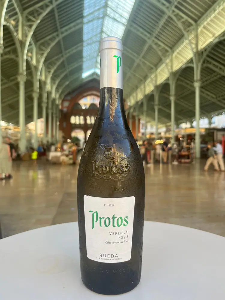 botella protos vino blanco verdejo con mercado de colón de fondo